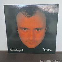 Front cover of the 'No Jacket Required' album by Phil Collins with a close-up photo of Phil Collins' face and album title and artist's name in white text