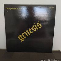 Front cover of the Genesis album "From Genesis to Revelation" showing black glossy cover with gold gothic lettering and London Records logo.