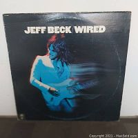 Front cover image of Jeff Beck Wired album showing Jeff Beck playing guitar with a blue motion blur effect on black background.