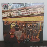 Front cover of The Beatles Reel Music vinyl album showing illustrated Beatles outside Capitol Theater with marquee listing songs from their films.