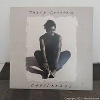Front album cover of Tracy Chapman's Crossroads showing her sitting barefoot in black and white photo.
