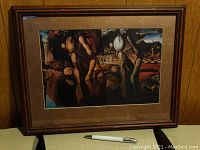 Framed print of surrealist painting showing reflection and abstract human forms in a wooded frame with brown matting.