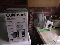 Photo showing the boxed Cuisinart 12-cup programmable coffeemaker with model number DCC-1100C and product features.