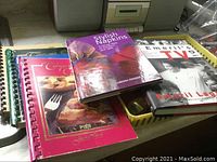 Four cookbooks stacked, including Company's Coming and Stylish Napkins with spiral bindings visible
