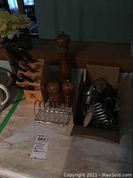 Photo of Henkel wooden knife block with at least six knives, large wooden salt and pepper grinders with a metal stand, all on a countertop next to cardboard boxes.
