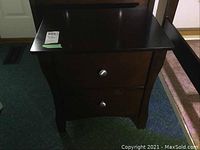 Front view of the dark wood 2-drawer end table with metal knobs, showing the table legs and tabletop.