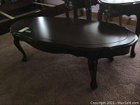 Side-angle view of the wooden coffee table showing carved legs and worn surface.