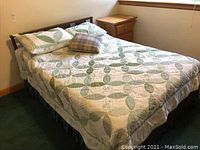 Full view of bed with green and white quilt and pillows on it, showing items as a set