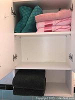 Cabinet shelf with folded towels in teal, pink, and black colors
