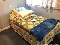 Fully made adjustable twin bed with bedding, pillows, and throw blanket.