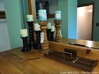 Full view of wooden tray and four candle holders with candles in front of mirror