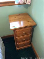 Full view of pine cabinet showing three drawers with wooden knobs and flat top surface.
