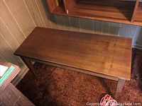 Full side view of rectangular wooden piano bench showing tapered legs and overall structure.