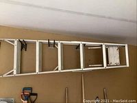 Aluminum step ladder hanging horizontally on wall showing full length with visible step tread patterns and platform.