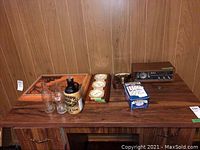 Entire lot on a wooden table including wood art picture, barometer, Sony radio, vintage bottle, dominoes tin, and volt reader.