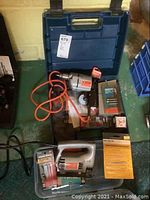 Overview photo of Black & Decker electric drill, jig saw, drill bits and saw blades on blue storage case.