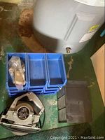 Sears circular saw, blue plastic storage bins, black hardware storage drawers on green floor near a water heater.