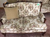 Front view of the loveseat showing floral upholstery and one beige cushion