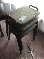 Five vintage stacking stools stacked; two with floral patterned cushioned seats, three with black metal frames and thinner cushions.