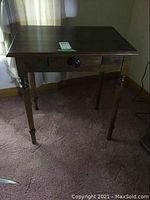 Image of the small solid wood table with single drawer from front angle showing the drawer and turned legs.