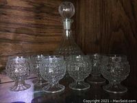 Full set including glass decanter with stopper and six matching hobnail pattern glasses lined up.