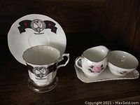 MacIntosh teacup and saucer featuring black and red tartan banners and a crest with compass design