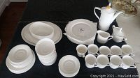 Overhead shot of white Spode bone china dinnerware set arranged on black cloth.