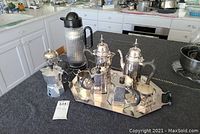 Overview: silver-plated tea set on tray, glass coffee press and aluminum percolator