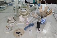 Overall view of assortment on countertop including dishes, decorative bird, Galileo thermometer, plates, pepper grinder and utensils in ceramic holder.