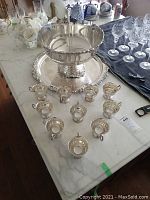 Complete punch bowl set: large bowl on pedestal, serving tray underneath, 12 cups visible (24 included) arranged around