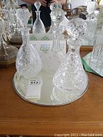 Three cut crystal decanters on round mirrored base from front view