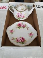 Teapot and one cake plate showing floral design and gold trim