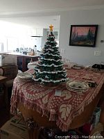 Full view of ceramic Christmas tree on table with plates around
