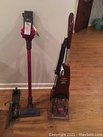 Both Dyson stick vacuum with accessories and Bissell QuickSteamer side by side