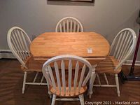 Photo showing rectangular wood top table with four white and natural wood chairs arranged around it on hardwood floor.
