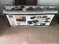 Original box of Camp Chef Explorer 2 burner outdoor grill showing promotional images and usage contexts.