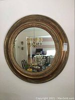 Front view of the round giltwood framed mirror showing ornate carved detailing and reflective surface.