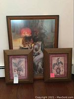 Full view of trio of framed artworks: one large Victorian lady print and two smaller botanical prints with textured frames.