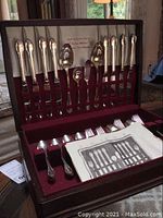 Full view of the Rodgers 52-piece silver plated flatware set displayed in original wooden chest with burgundy lining, showing flatware arranged in slots.
