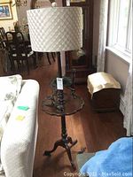 Full view of the three-legged lamp table with built-in lamp and lampshade beside sofa in living room