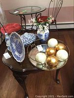 Wide view of Spode plate, vase with faux flowers, figurine, tureen, and mirrored tray with decorative balls on wood table