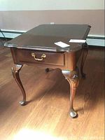 Side view of Ethan Allen rectangular side table showing one cabriole leg and drawer with brass handle