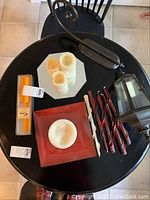 Top-down photo of assorted candles and lantern on black round table.