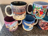Close up showing 5 Disney mugs including 101 Dalmatians, Alice in Wonderland, Fantasia and others