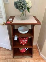Front view of the wooden shelf tower showing three shelves with some items placed for scale (not included). Visible surface scratches on wood.