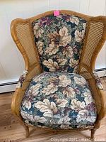 Front view of wicker wingback chair showing floral fabric upholstery and wooden frame