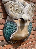Front view of metal owl wall decoration on brick wall showing detailed eyes and wings