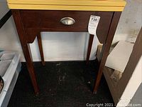 Wooden vintage sewing machine table with yellow top and single drawer with silver handle, photographed showing front and side views.
