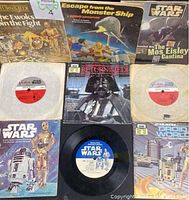 Overview photo of 8 Star Wars collectibles including books and 45 RPM records arranged on flat surface, showing book covers with characters like Darth Vader, R2-D2, C-3PO, Ewoks, and scenes from Star Wars films.