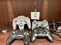 Photo of four wired video game controllers on wooden surface